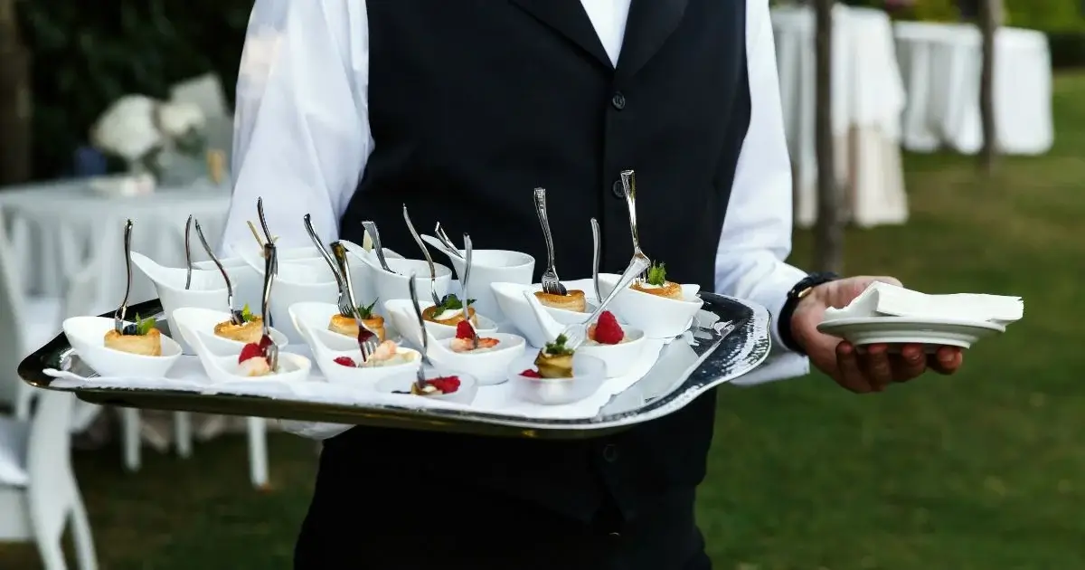 Server carrying appetizers at outdoor wedding reception